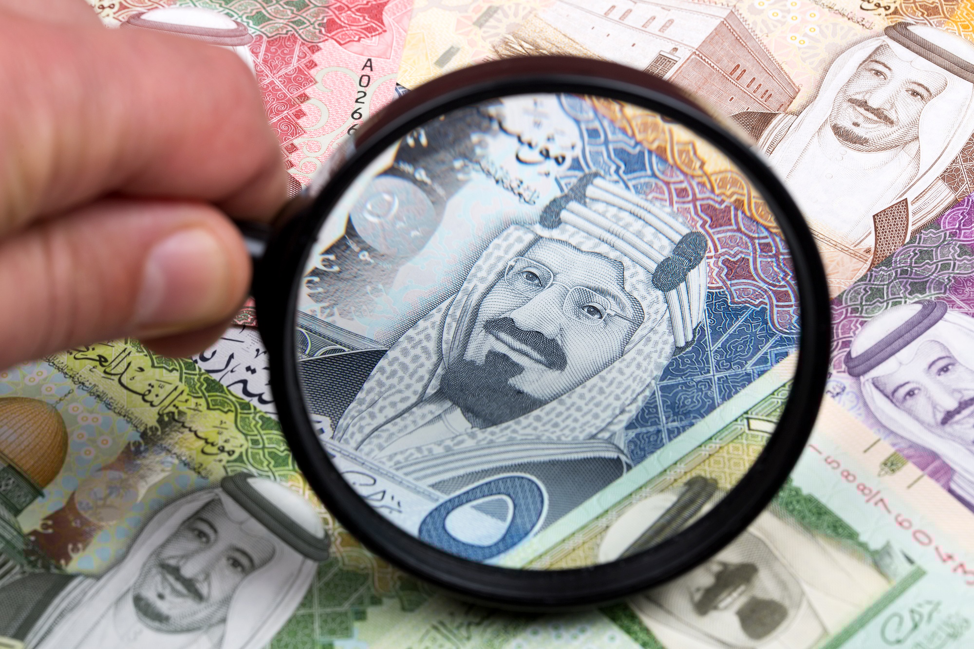 Saudi riyal in a magnifying glass